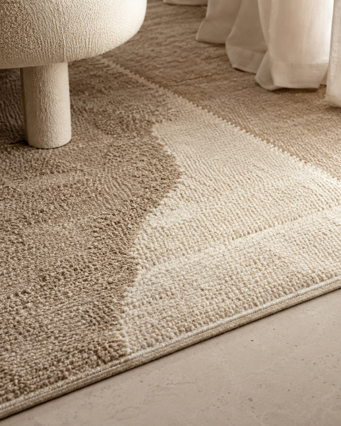 Close view of a wool rug's looped pile and bound edge against a stone floor