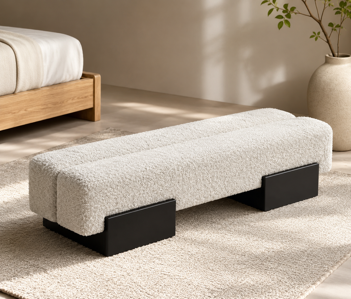 Brea Bench in cream flannel with a rolled top edge, on two black block feet, at the end of an oak bed